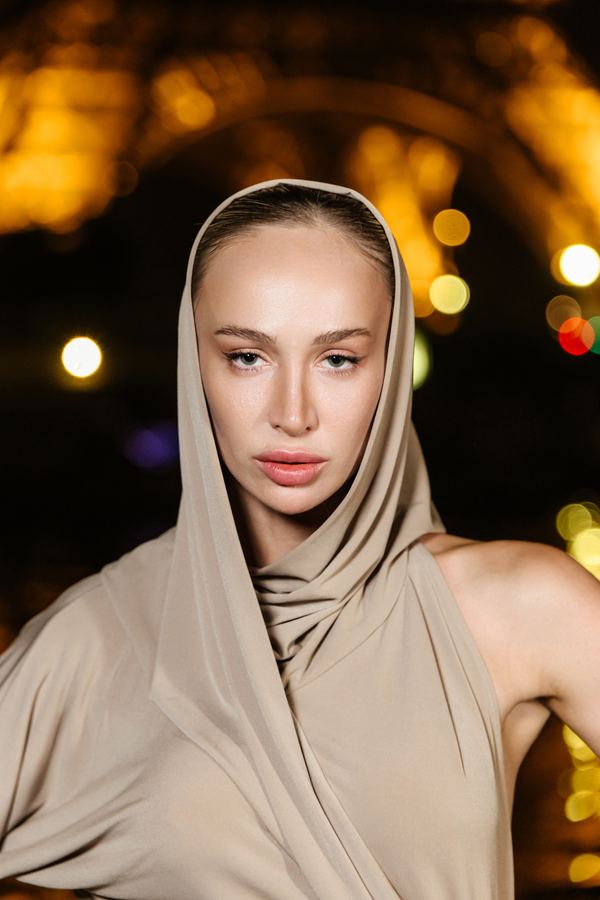 Portrait of a woman in beige hood, bare shoulder, Eiffel Tower, Paris at night