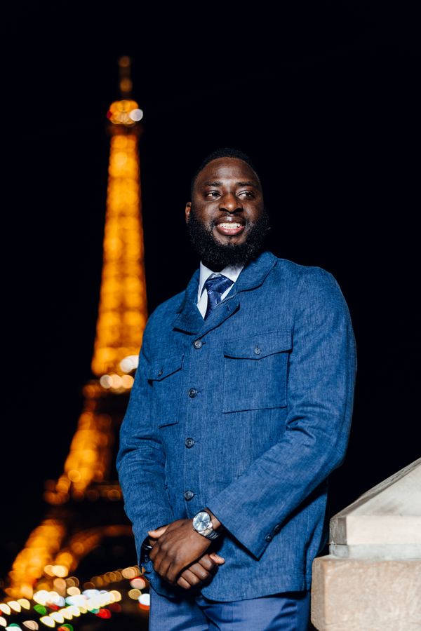 Portrait of a man in blue denim suit, tie, Eiffel Tower, Paris at night