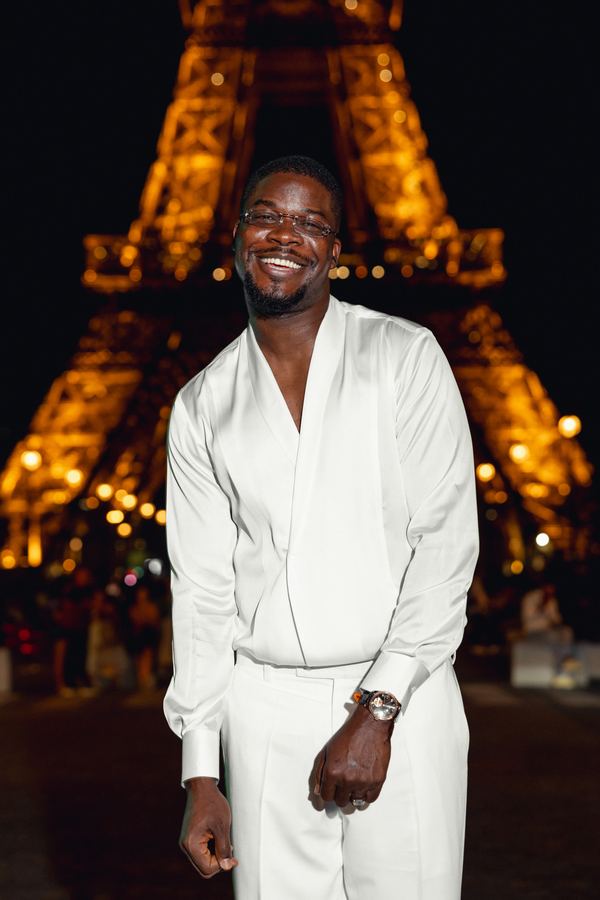 Portrait of a man in white shirt, white trousers, Eiffel Tower, Paris at night