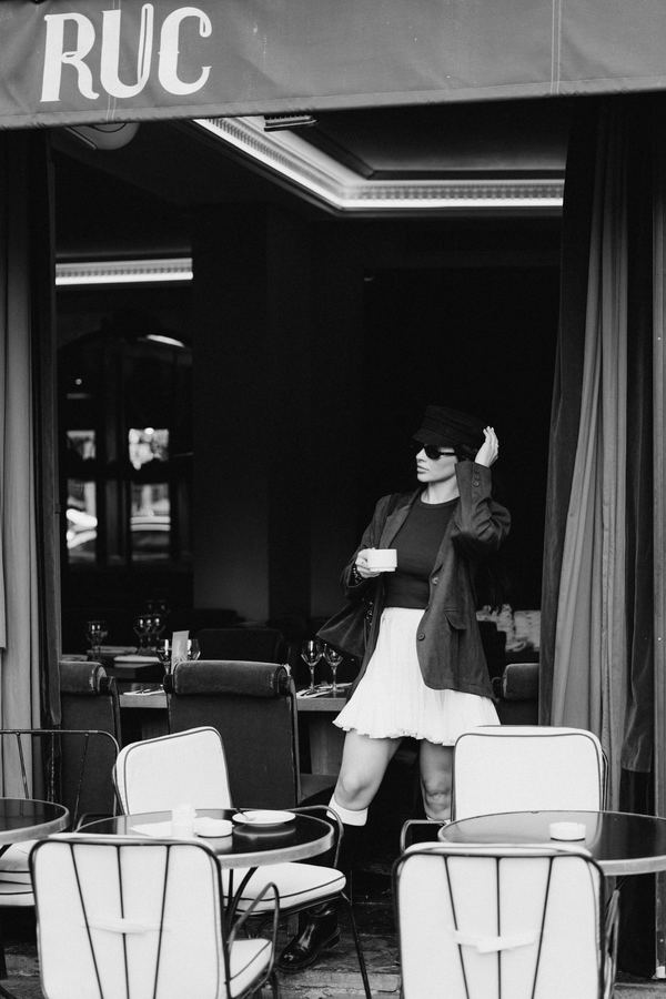 Street style: brown blazer, black sailor cap, white pleated skirt, cafe terrace, Paris