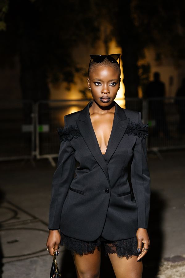 Street style at Paris Fashion Week: black blazer, lace trim, black clutch, show venue entrance, Paris at night