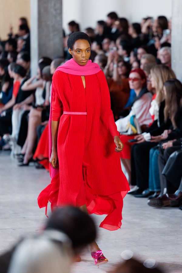 Street style at Paris Fashion Week: red pleated dress, pink scarf, show venue entrance, Paris