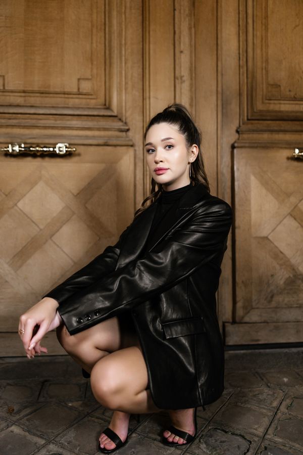 Portrait of a woman in black leather jacket, black mini dress, heels, wooden door, Paris