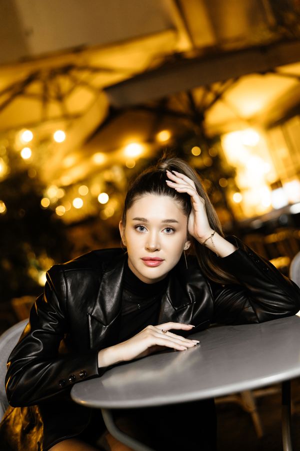 Portrait of a woman in black leather jacket, black turtleneck, cafe terrace, Paris at night