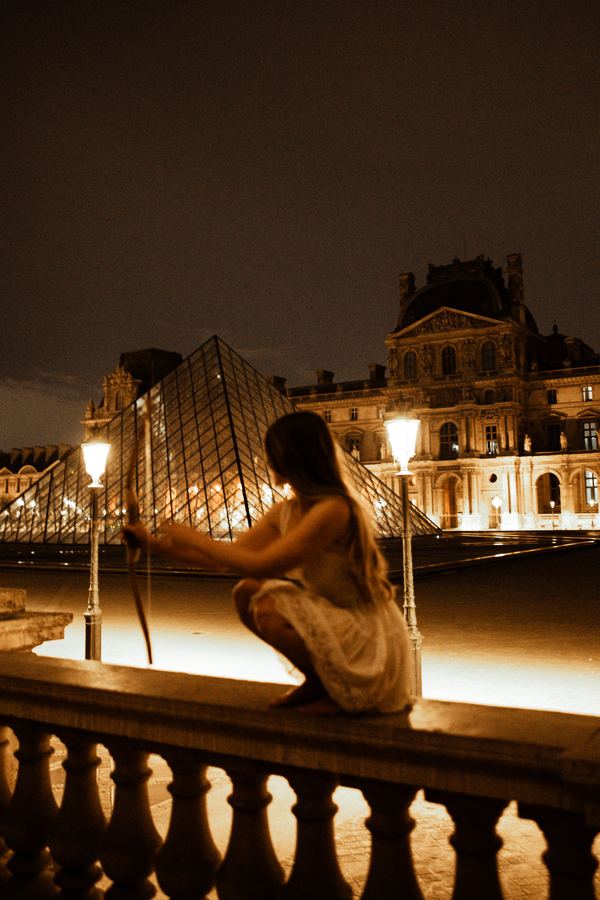 Portrait of a woman in beige dress, Louvre pyramid, Paris at night