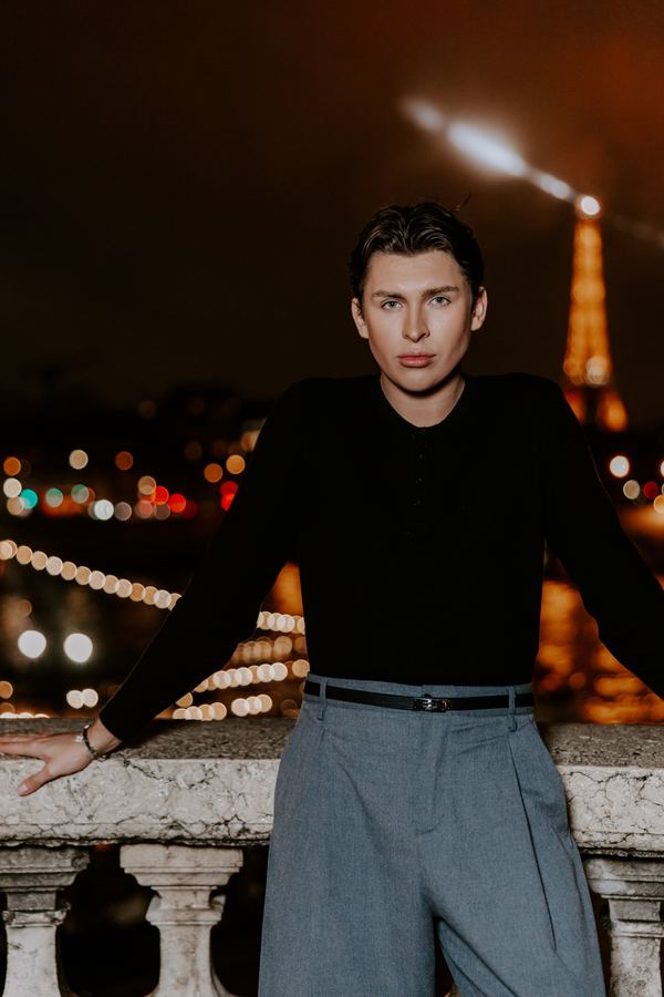 Portrait of a man in black henley, grey trousers, Eiffel Tower, Paris at night