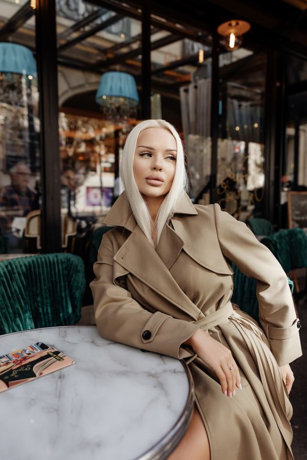 Portrait of a woman in beige trench coat, belted, cafe terrace, Paris