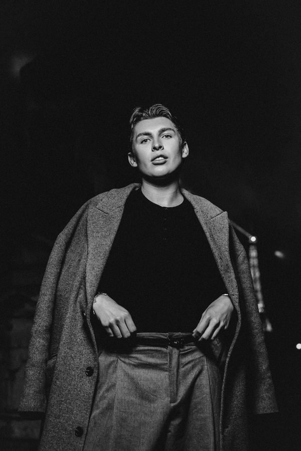 Portrait of a man in grey long coat, black top, Paris at night