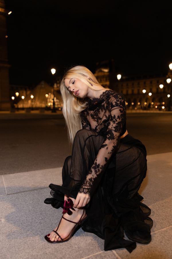 Portrait of a woman in black lace top, black sheer skirt, red heels, Louvre pyramid, Paris at night