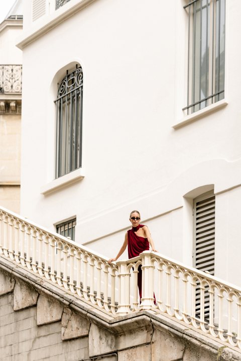 Wide view of a red dress and pale Parisian façades